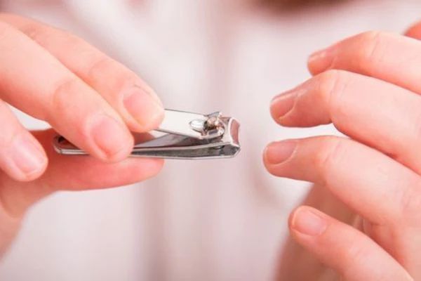a person using nail clippers to trim their fingernails