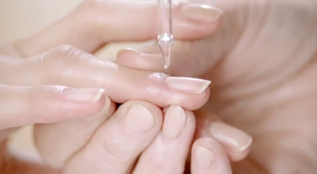 person applying oil to soften cuticles