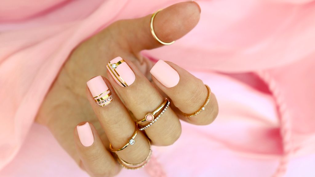 square shaped pink acrylic nails with gold accents on the ring finger.