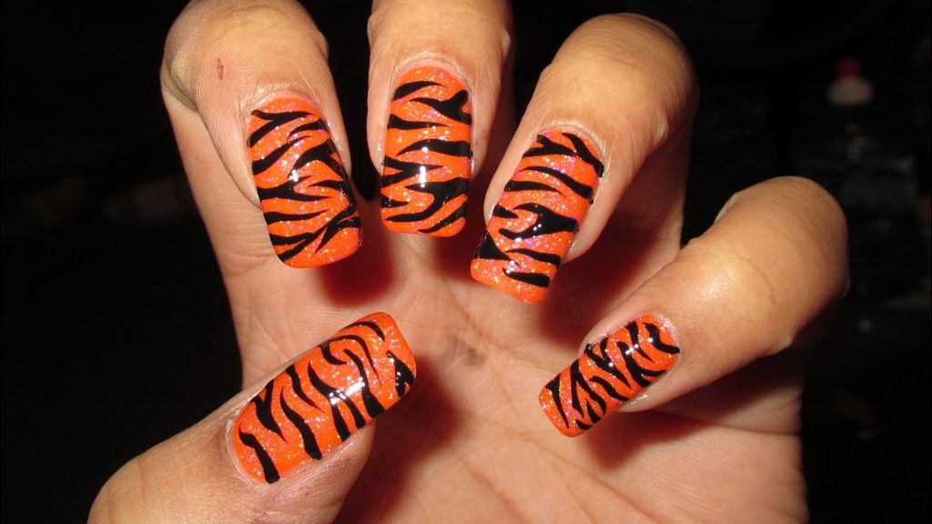 tiger print nail art uses vertical striping tape and high contrast colors like black stripes on an orange base.
