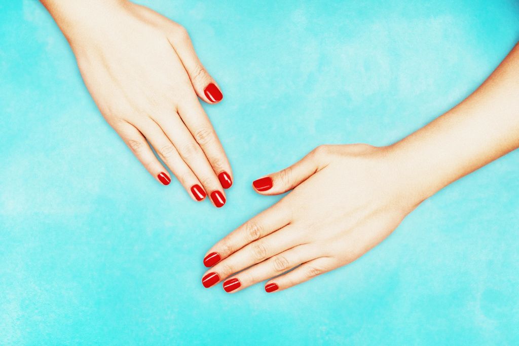woman painting nails a bright blue-red color